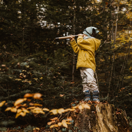 Schatzsuche im Wald Kind hebt Fernrohr während dem Kindergeburtstag im Herbst
